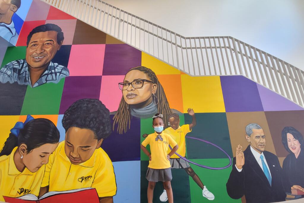 Student standing in front of mural on stair wall